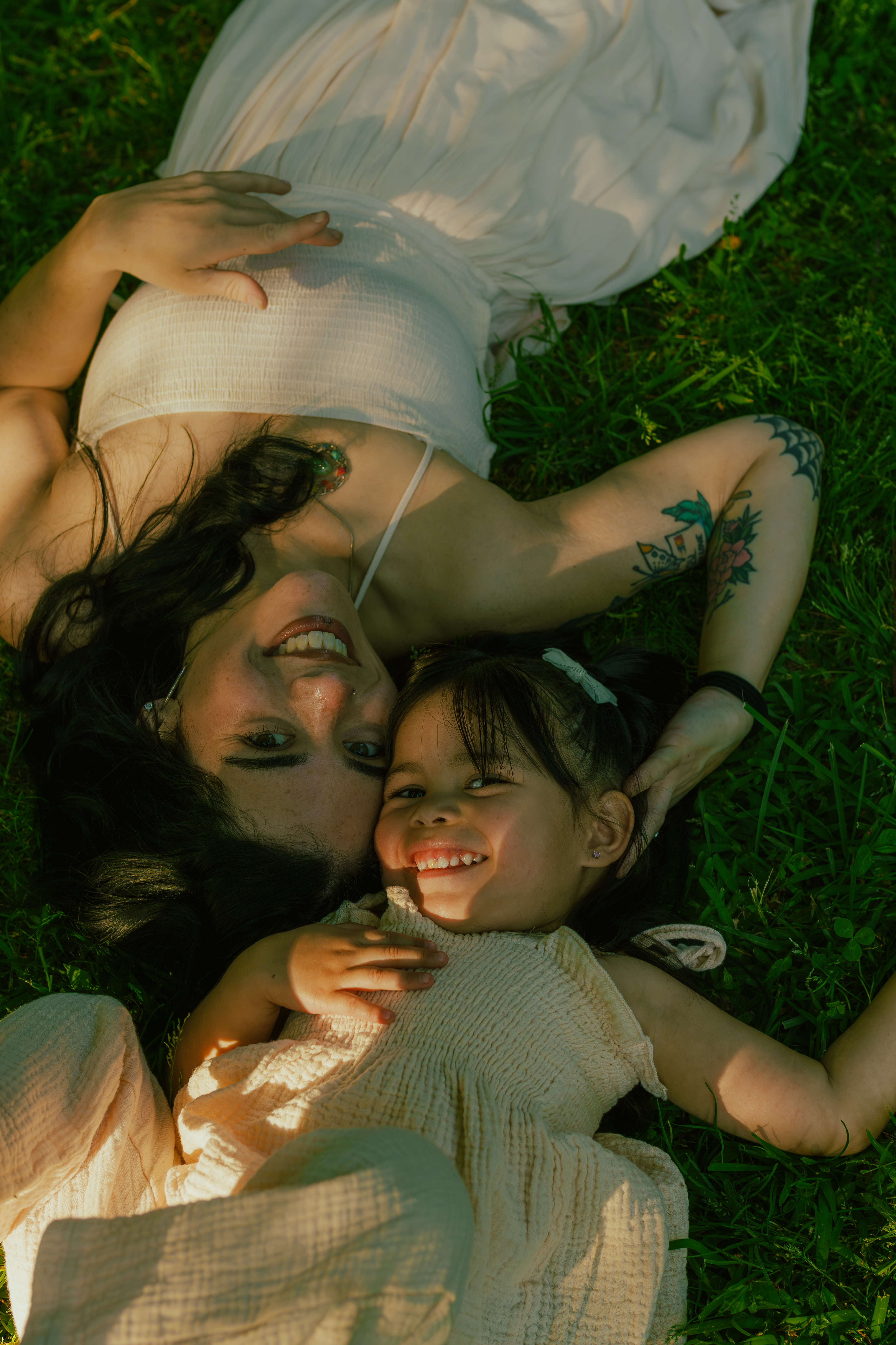 Mom and daughter laying down in the grass