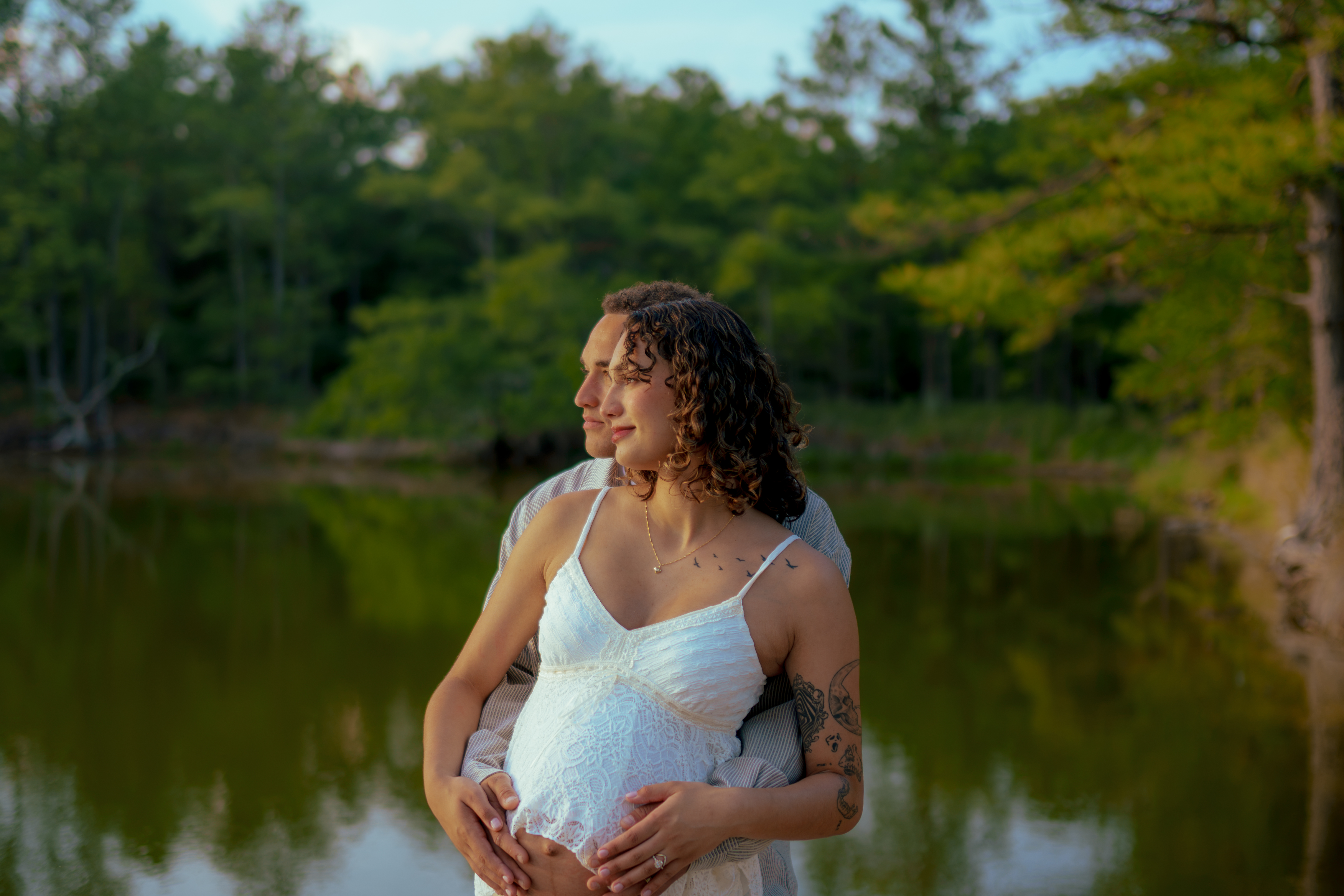 pregnant woman and husband embracing in the woods